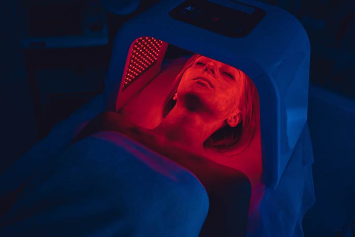 A woman having red light therapy on her face