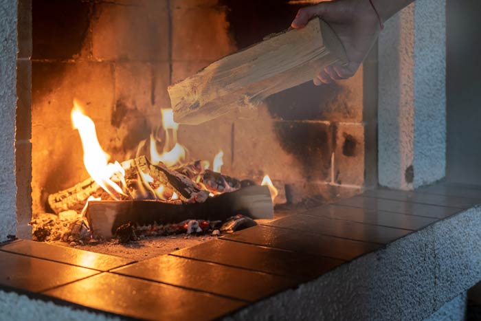 A man putting a log on a fireplace
